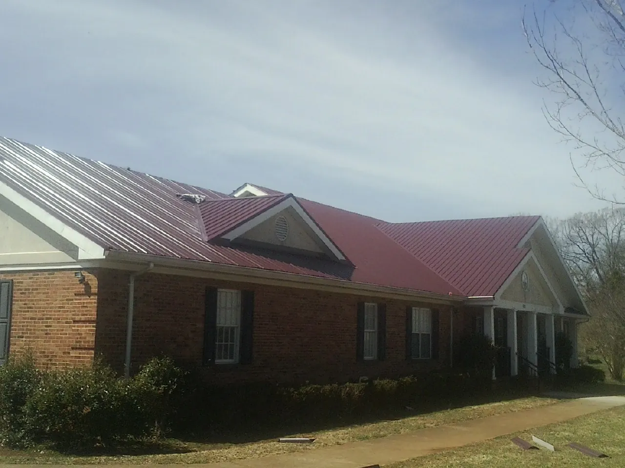 Red metal roof with gabled entries on a long brick building in Lawn