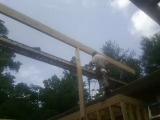 Carpenter setting a ridge beam over a new addition frame — Ice Dam Removal by Roofing Brothers in Lawn