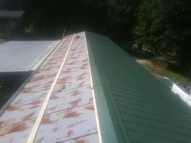 Old rusted panels beside newly installed green metal roofing — Wind Damage Roof Repair by Roofing Brothers in Lawn