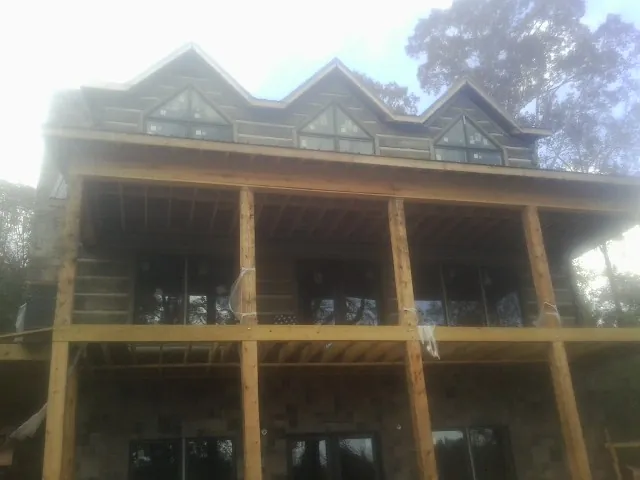 Dormers and porch framing on a large log home under construction — Roof Coating work by our crew in Lawn