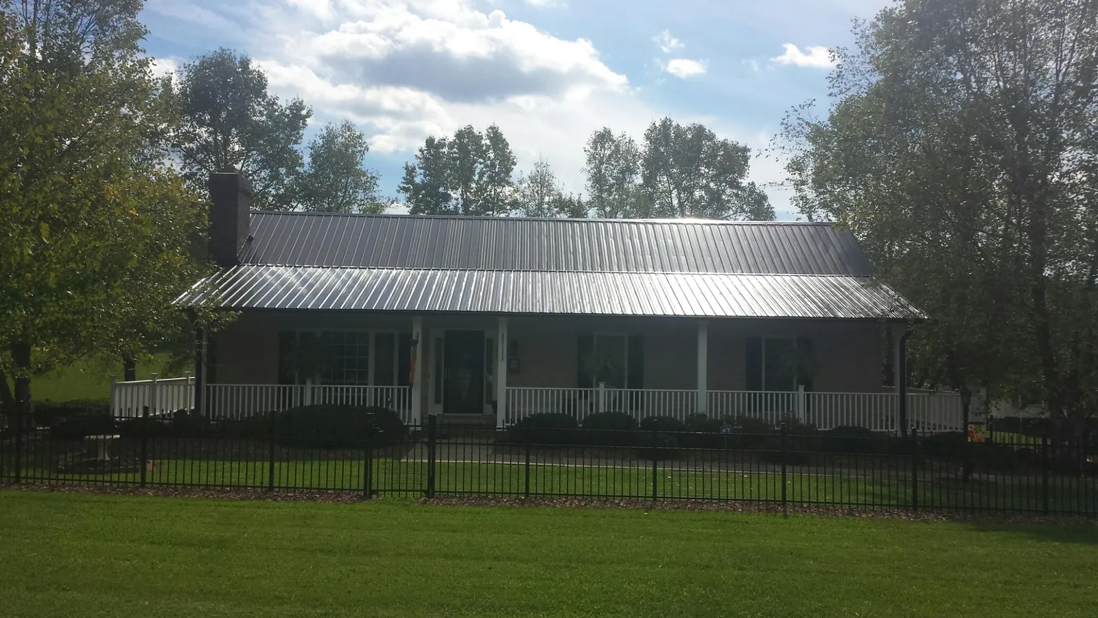 Gray metal roof on a brick ranch with a full width front porch — Gutter Guard Installation work by our crew in Lawn