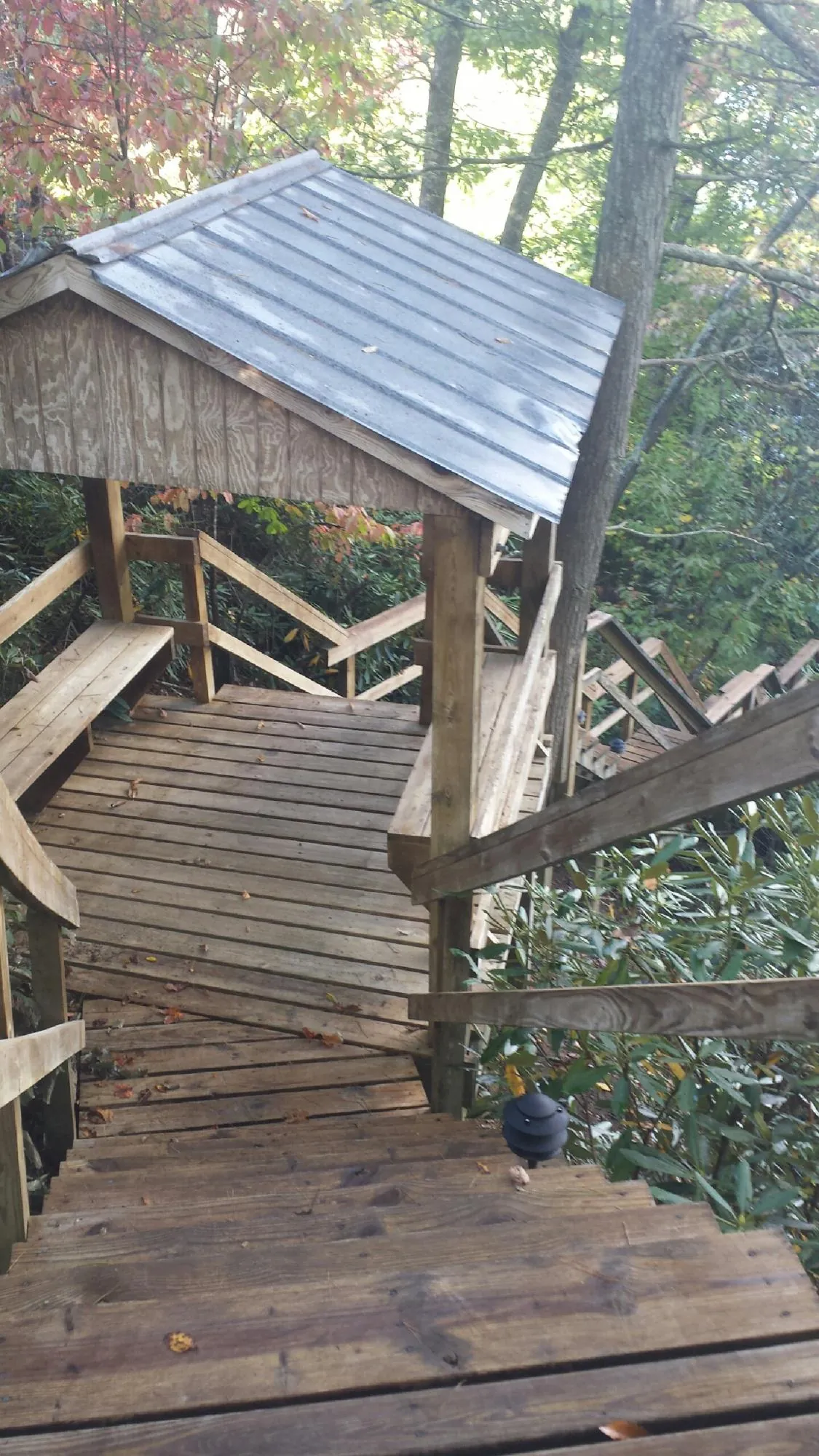 Metal roofed shelter over wooden steps on a wooded walkway — Skylight Repair & Installation work by our crew in Lawn