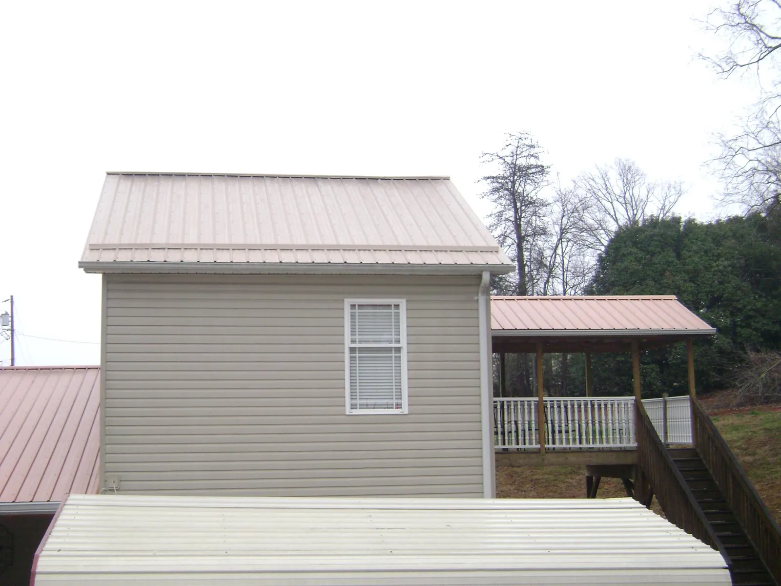 Tan metal roofs on a two story addition and attached porch, from a Roof Replacement job in Lawn