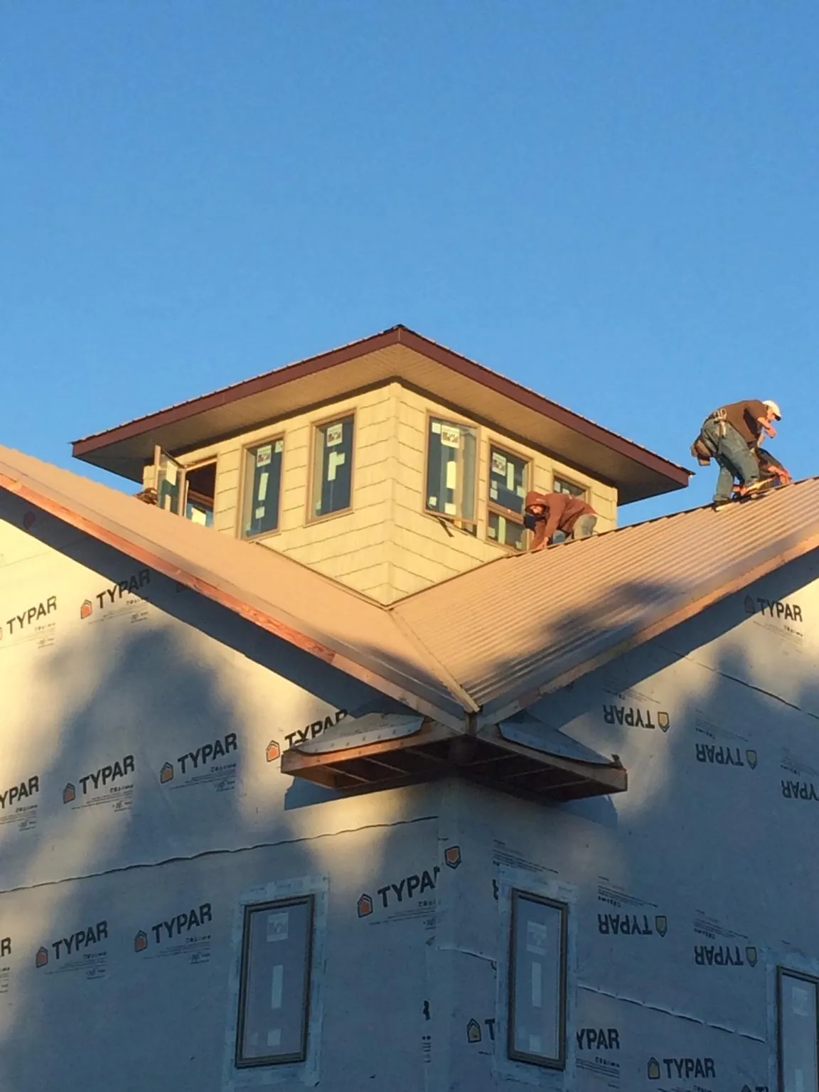 Roofers working around a rooftop cupola on a new metal roof at sunset — Roof Waterproofing in Lawn by Roofing Brothers